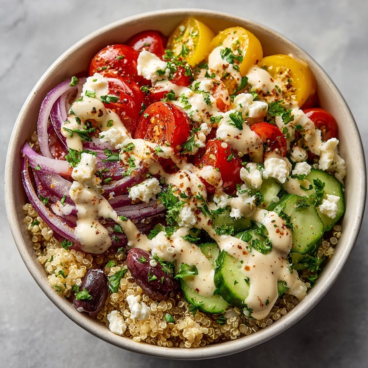 Colorful Mediterranean Quinoa Power Bowl topped with fresh vegetables, feta, and drizzled lemon tahini dressing