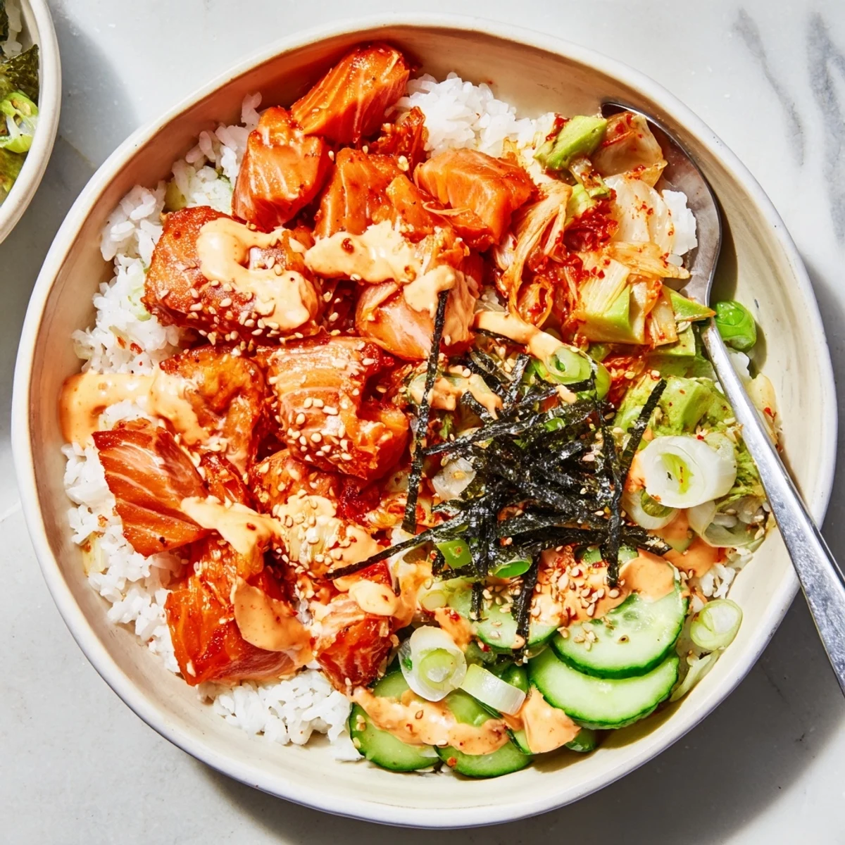 Crispy salmon rice bowl topped with spicy mayo, kimchi, and fresh avocado slices.  
