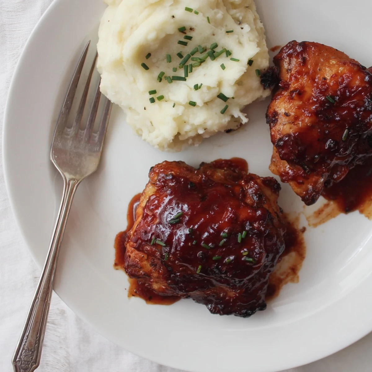Succulent honey BBQ chicken thighs paired with creamy garlic mashed potatoes on a plate.  