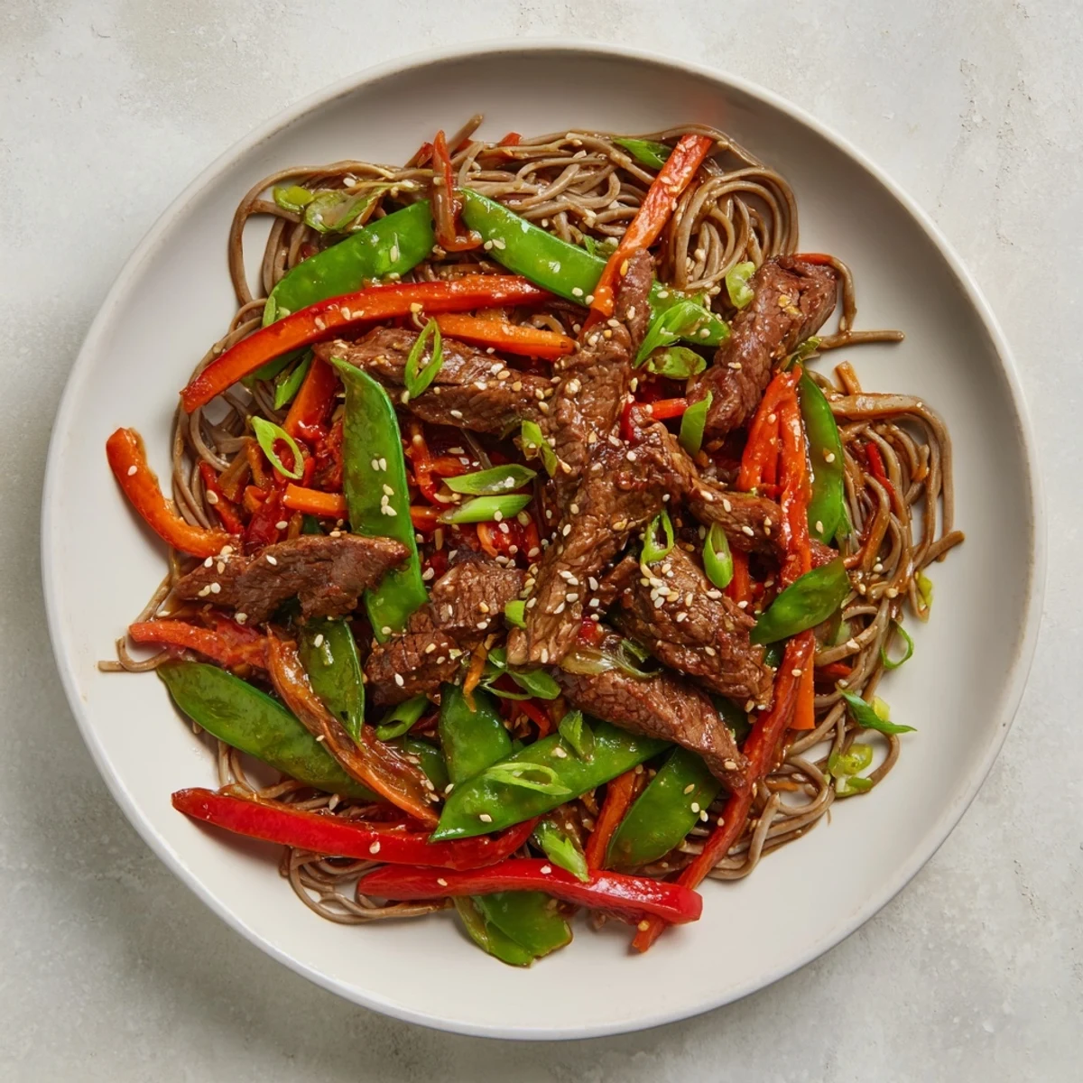Steaming Teriyaki Beef & Noodle Bowl with glistening sauce, topped with sesame seeds and green onions.