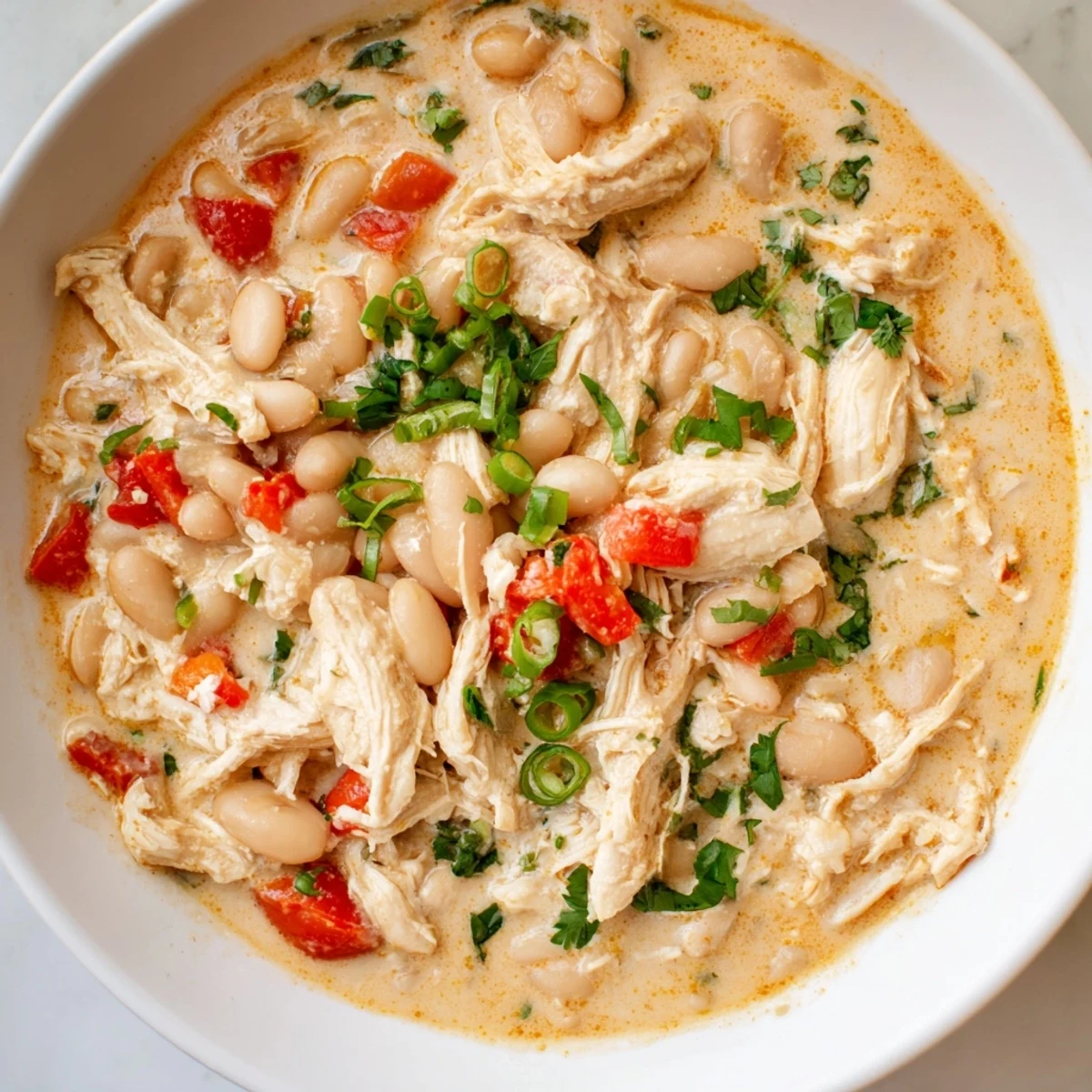 Creamy white chicken chili with beans, garnished with fresh cilantro, ready to be served hot.
