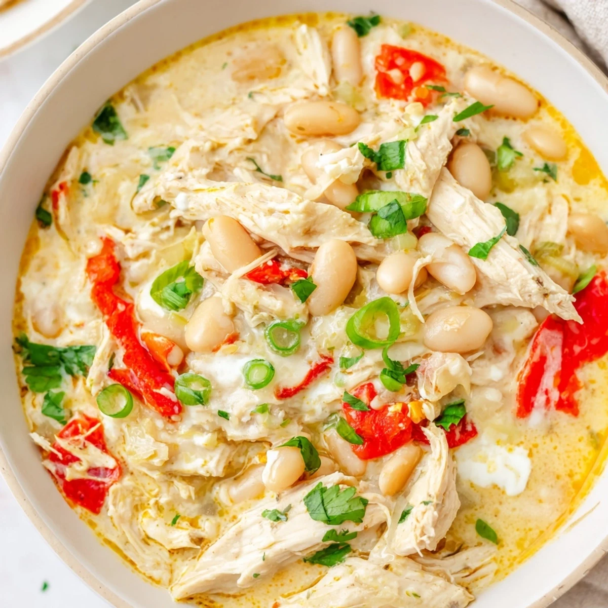 Close-up of a flavorful creamy white chicken chili with beans, showcasing its rich texture and spices.