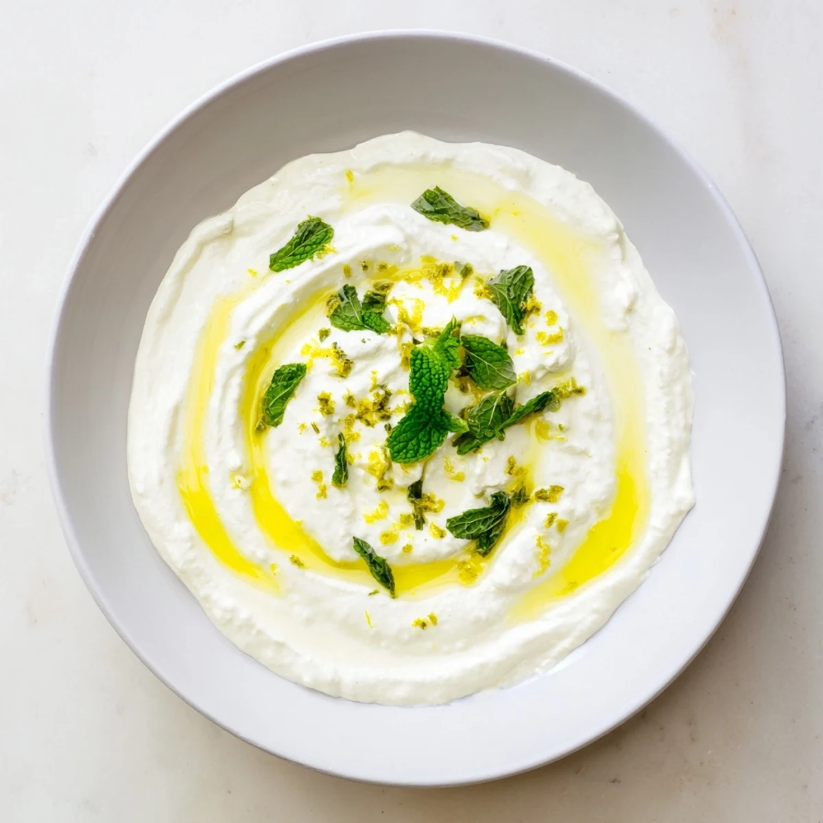 Creamy whipped feta dip with vibrant lemon-mint drizzle, ideal summer appetizer.