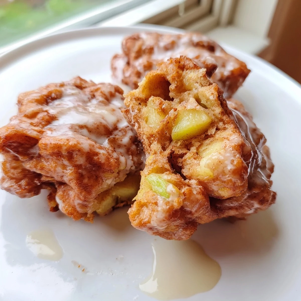 Golden, fried homemade Apple Fritters, glazed and ready to eat, with cinnamon and nutmeg aromas.