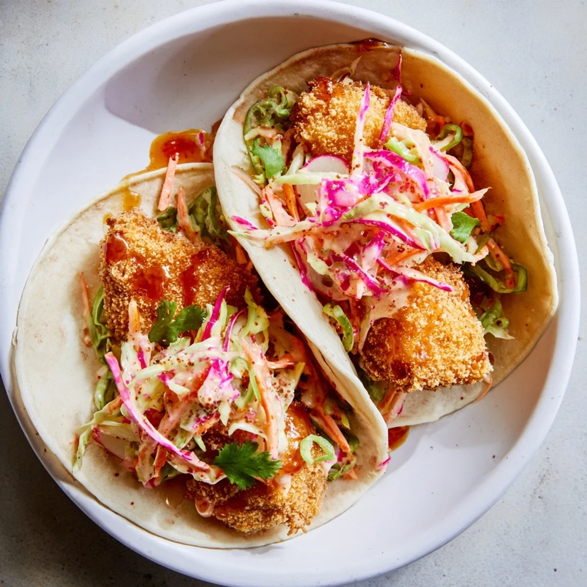 Golden-brown, crispy Hot Honey Chicken Tacos are nestled in warm tortillas with a spicy-sweet drizzle.