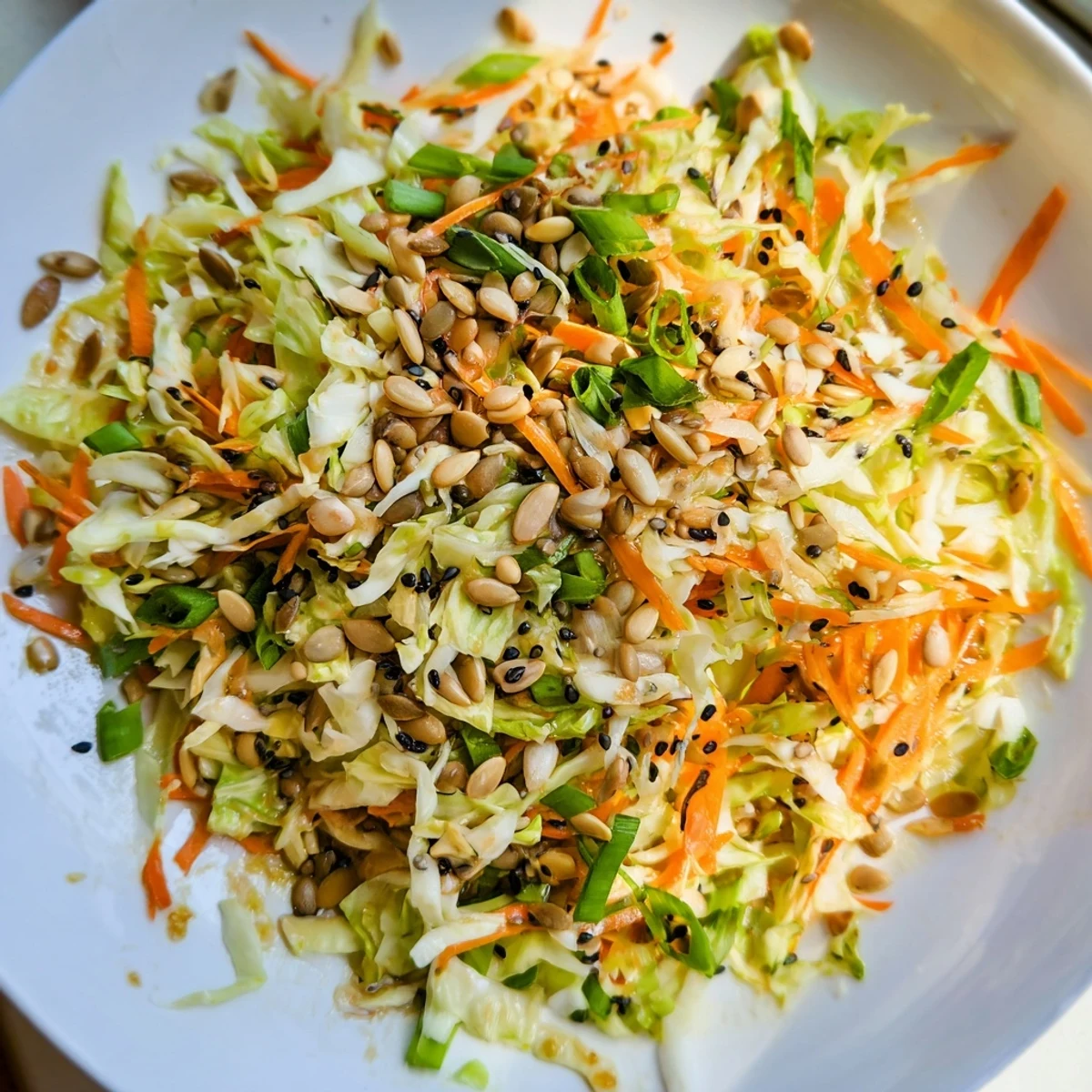 A colorful Cabbage-Core Slaw Salad displays crisp shredded cabbage, carrots, and sesame seeds after tossing.