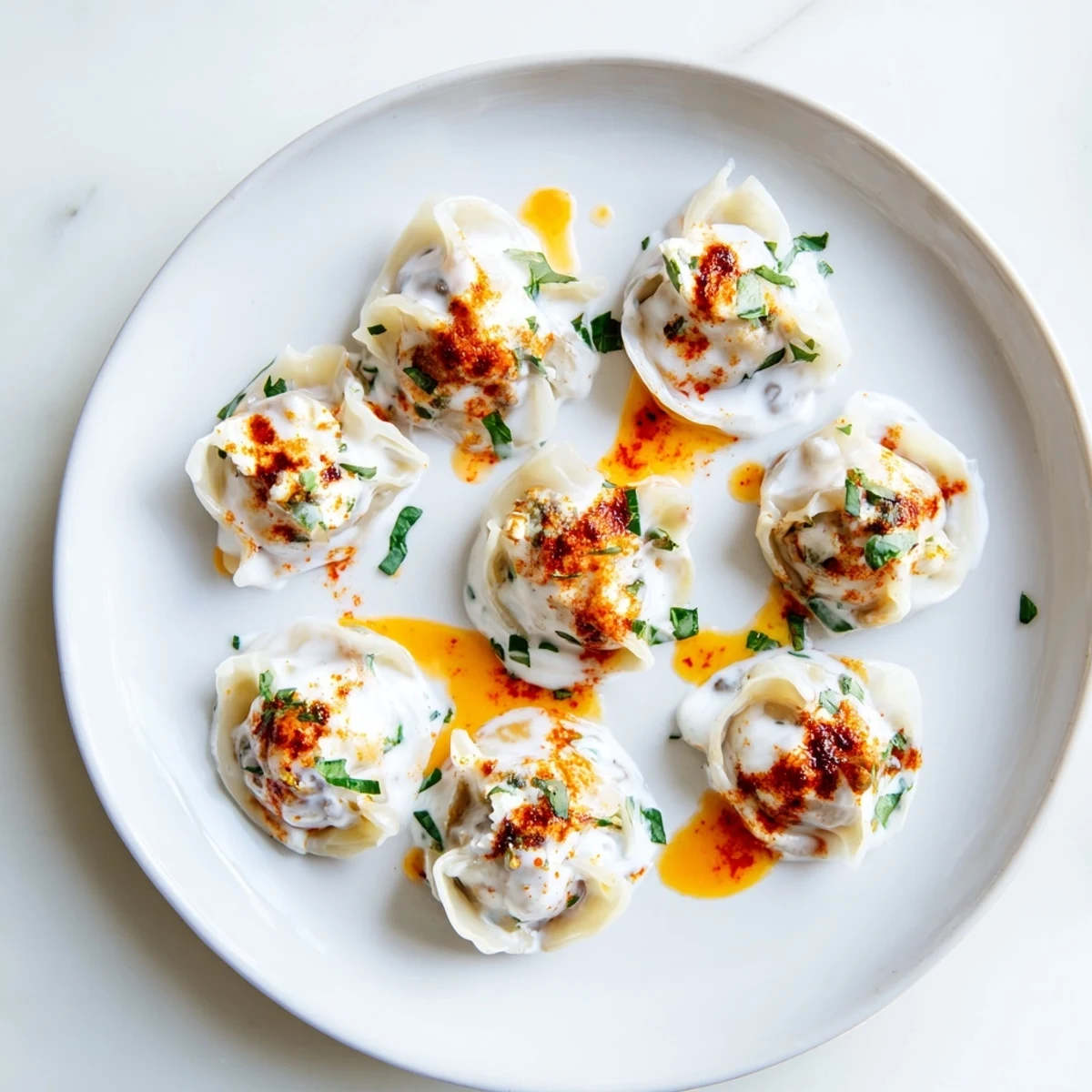 Golden Turkish cheesy manti dumplings, drizzled with spiced butter and creamy yogurt, delicious.