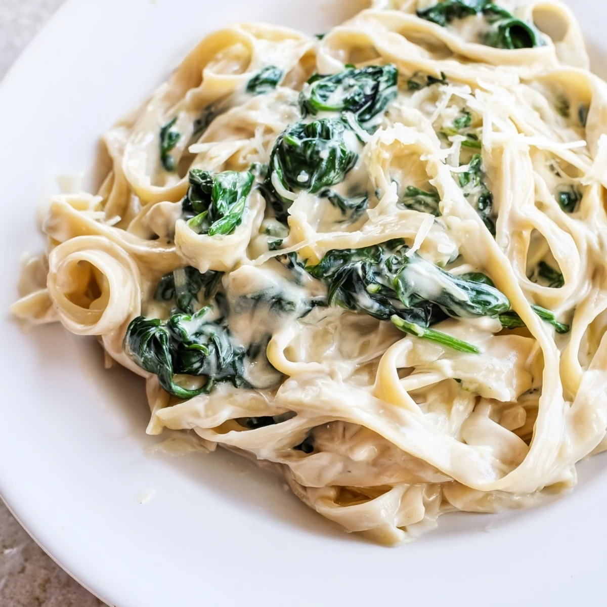 Garlicky cream sauce clings to every strand of pasta, with vibrant green spinach adding a fresh bite.