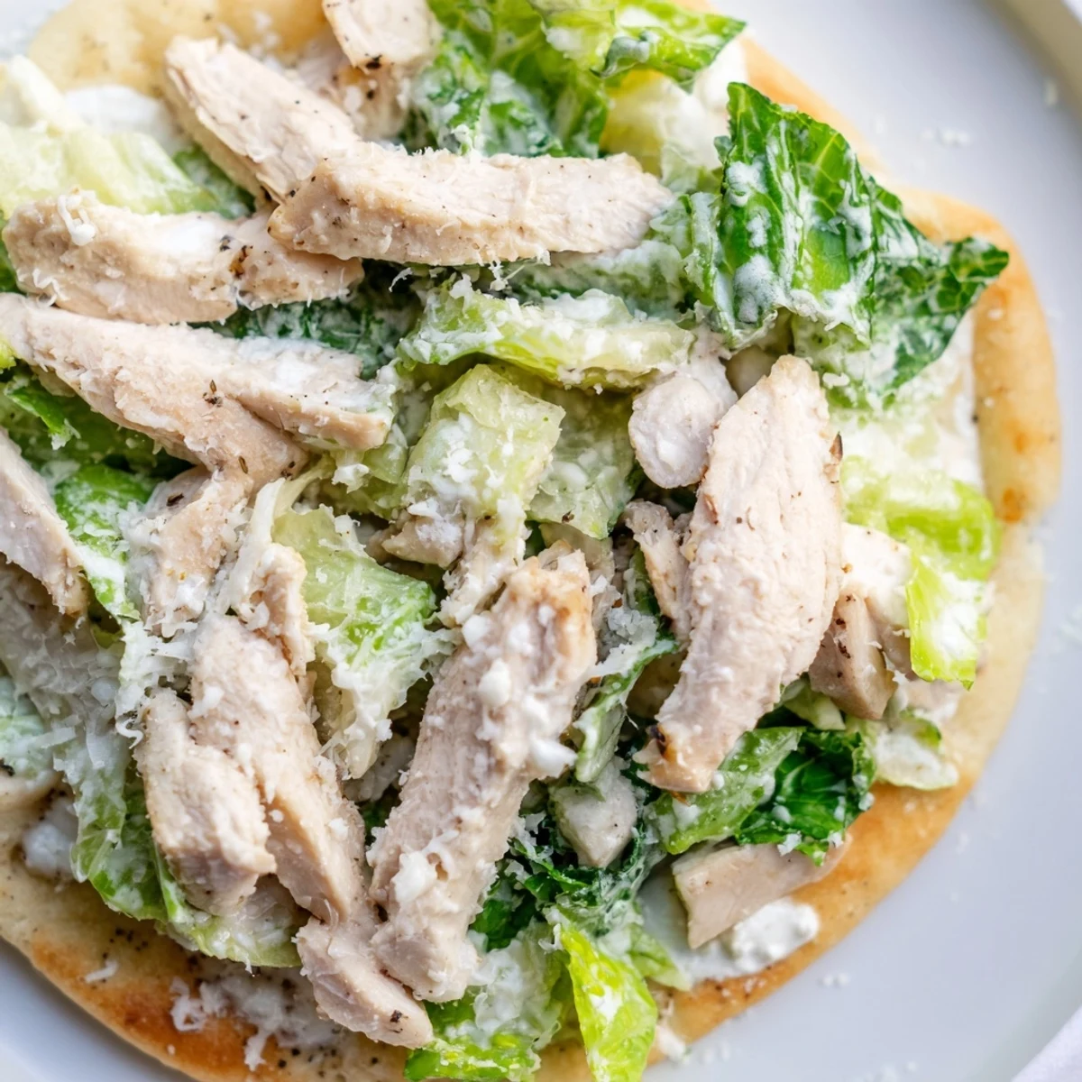 Golden-brown, crispy flatbread topped with juicy grilled chicken, fresh romaine, creamy Caesar dressing, and parmesan cheese, perfect for a light lunch or appetizer.