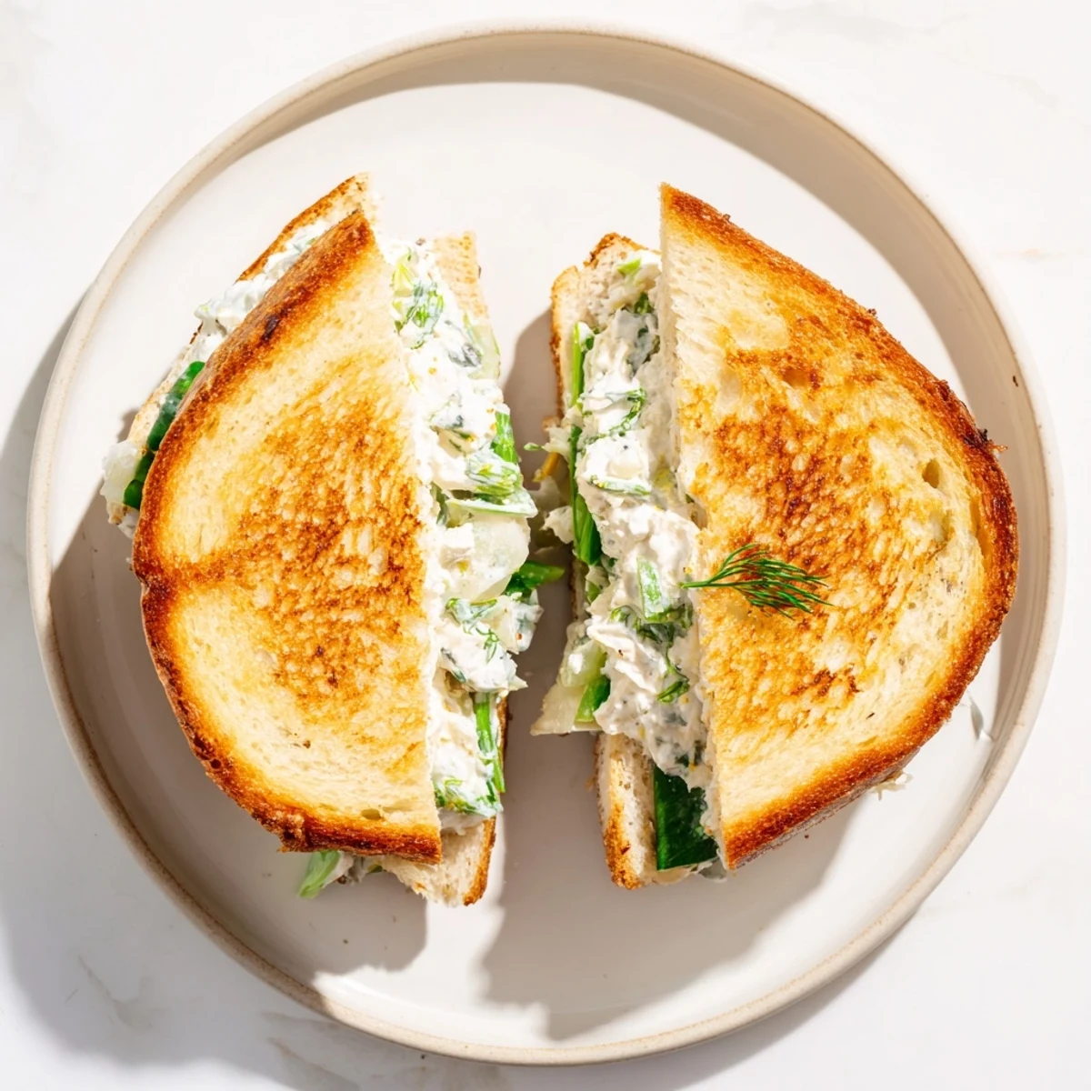 Toasted golden sourdough slices stuffed with creamy whipped feta spring grilled cheese, topped with fresh dill and lemon zest.