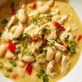 A steaming bowl of creamy white chicken chili with beans, perfect comfort food, ready to enjoy.
