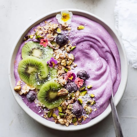 Vibrant smoothie bowls with purple yam and pistachios, topped with fresh berries.  
