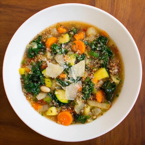 Steaming bowl of Minestrone with Quinoa & Winter Greens garnished with fresh parsley, ready to enjoy.