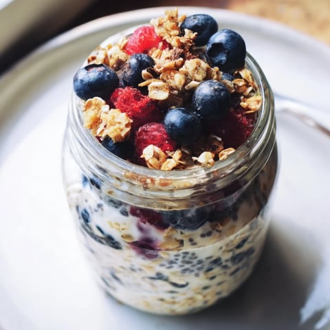 Jars of overnight oats layered high with fresh berries and crunchy granola for breakfast.