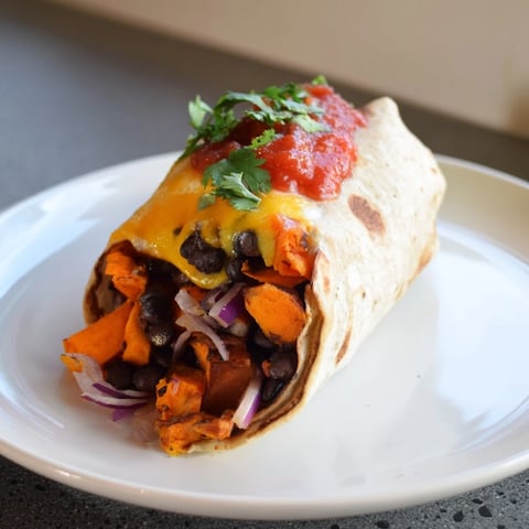 Steaming, savory Sweet Potato & Black Bean Breakfast Burrito, filled with roasted vegetables, ready to eat.