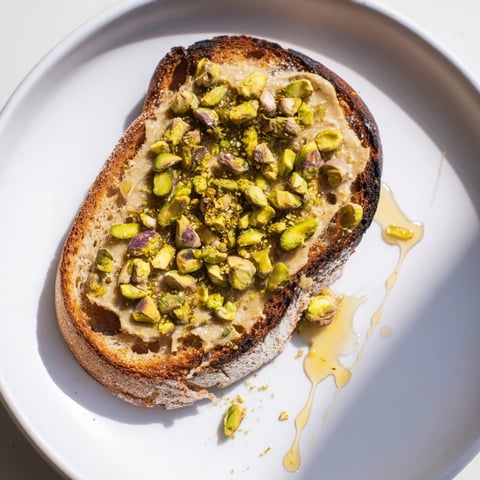 Golden-brown Pistachio Butter Toast topped with glistening honey and crunchy pistachios.