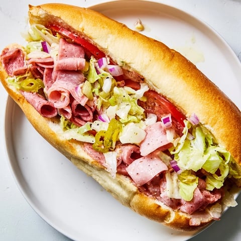 Chopped Italian Grinder sandwich overflowing with meats and cheese, ready to eat on a toasted hoagie.