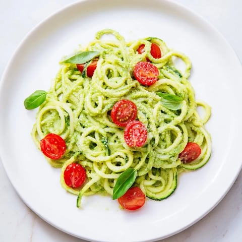 Vibrant avocado pesto zoodles, a healthy vegetarian meal bursting with fresh tomato flavor.