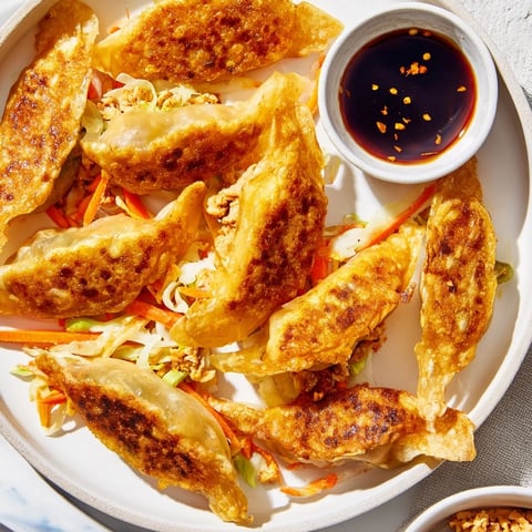 Golden-brown crispy rice paper dumplings, filled with savory meat, are served with dipping sauce.