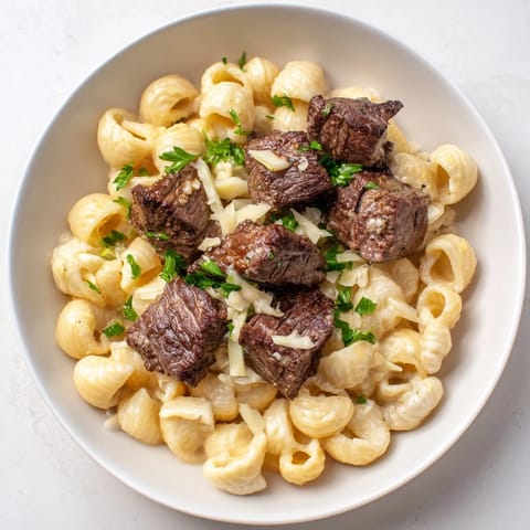 Golden seared Garlic Butter Steak Bites atop creamy cheesy shells, a comforting, delicious meal.
