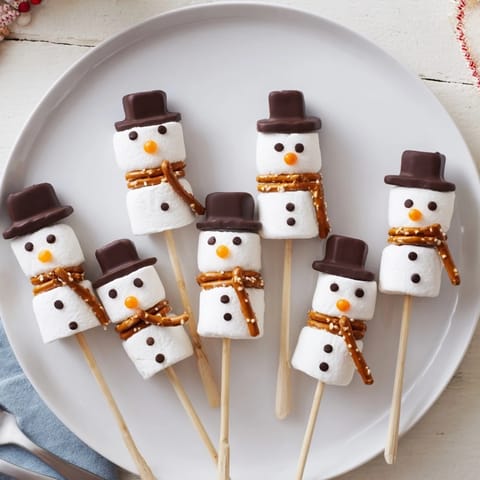 Easy-to-make marshmallow snowman stick arrangement, showcasing charming, decorated snowmen ready to eat.
