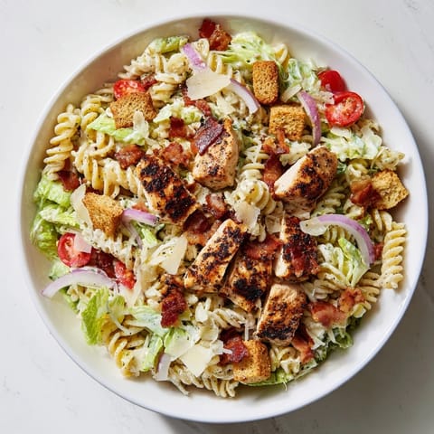 Tossed Chicken Caesar Pasta Salad, featuring bite-sized chicken, juicy tomatoes, and crunchy croutons in Caesar dressing.