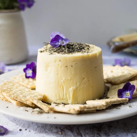 A close-up of The Obsidian Peak, showcasing the sharp cheddar cheese and charcoal-dusted almonds ready to serve.