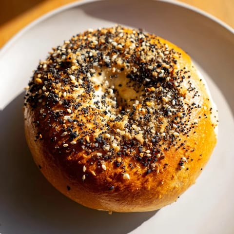 A close-up of savory Everything Bagel Yogurt Bagels, speckled with seasoning, steaming slightly.