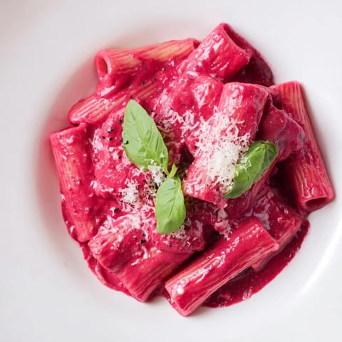 This Pink Pasta with Beet Cream shows cooked pasta enveloped in a smooth, pink beet sauce and Parmesan.