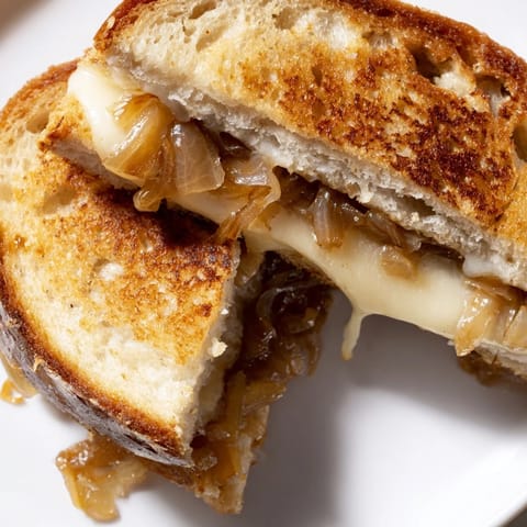 Buttery, crisp bread layered with slowly caramelized onions and gooey sharp cheddar, served warm and melty.