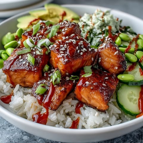 A freshly assembled Salmon Rice Bowl showcases fluffy jasmine rice, marinated salmon pieces, bright avocado slices, and a creamy drizzle of spicy sriracha mayo for dinner.