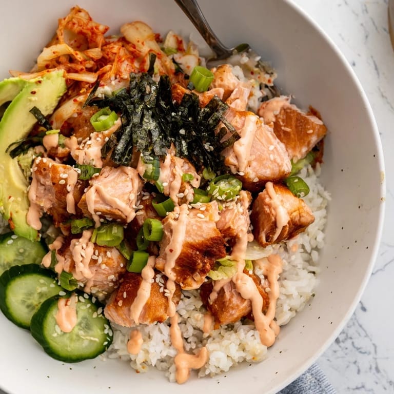 Delicious crispy salmon rice bowl, garnished with garlic, cucumber, and sesame seeds.  