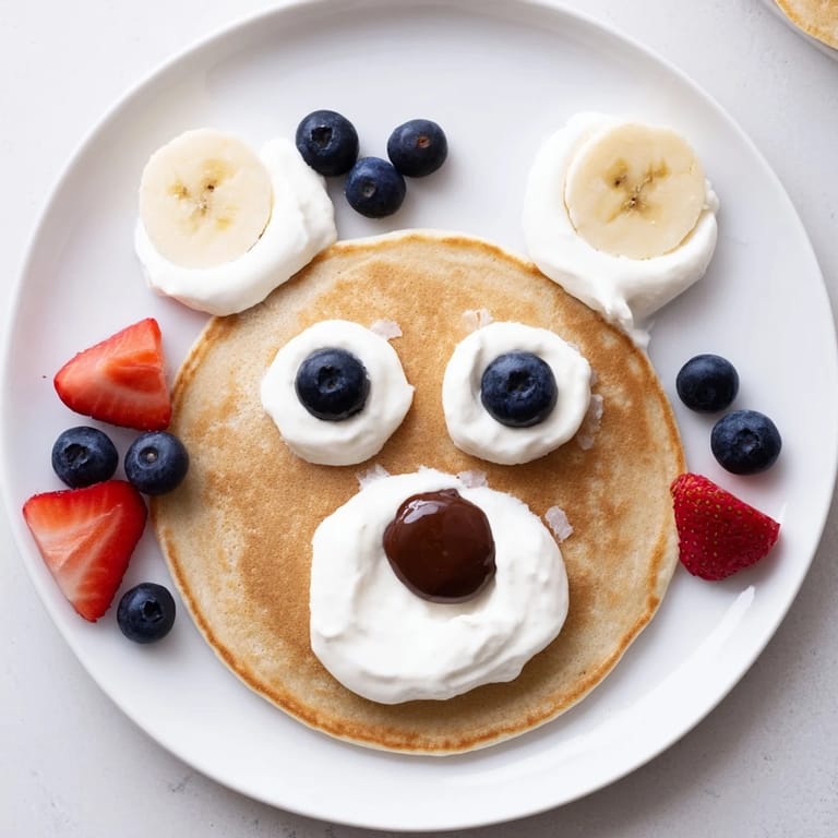 A family-friendly Polar Bear Pancake Stack Board: golden pancakes arranged with yogurt, bananas, and chocolate chips.