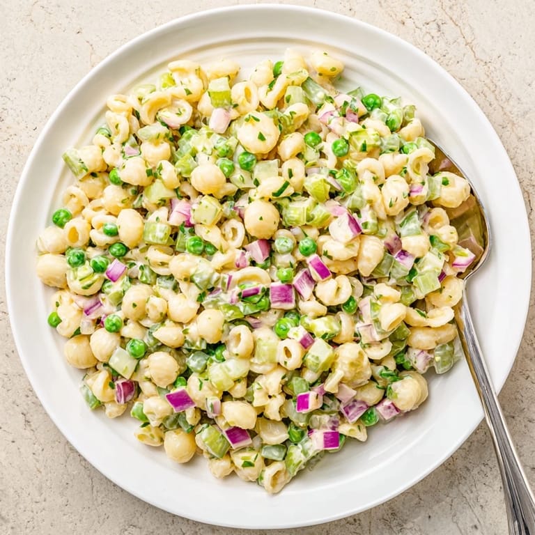 A chilled bowl of Creamy Dill Pickle Pasta Salad garnished with fresh dill, ready for a sunny picnic spread.  