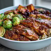 Hearty Maple Dijon Chicken Sweet Potato Bowls with roasted veggies and nutty rice, topped with pecans and cranberries.  